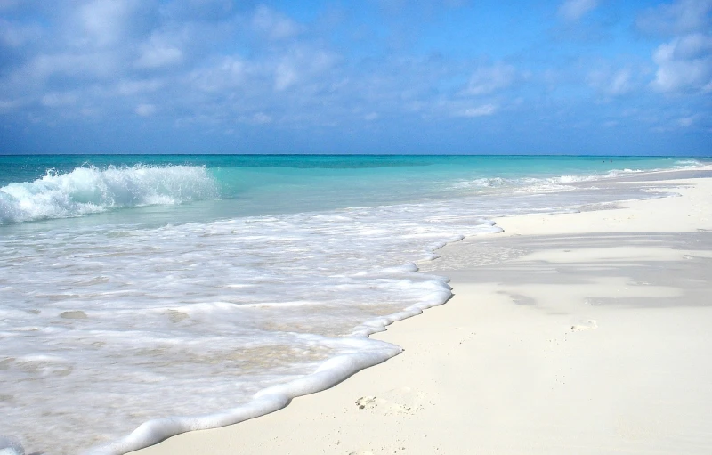 a person riding a surfboard on top of a sandy beach, by Alexander Scott, flickr, bahamas, pristine rippling oceanic waves, 3 / 4 extra - wide shot, wikimedia