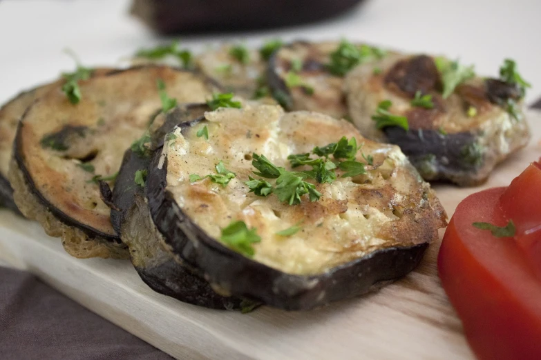 a close up of a plate of food on a table, by Maksimilijan Vanka, hurufiyya, eggplant, on a wooden plate, cheesy, patryk hardziej