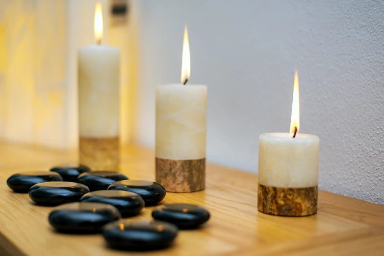 a couple of candles sitting on top of a wooden table, stone and wood, feng shui, sandra chevier, decoration around the room