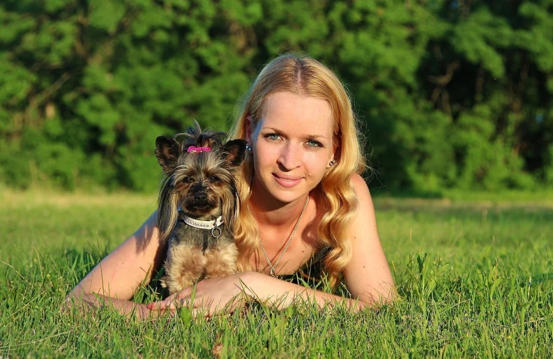 a woman laying in the grass with a small dog, a photo, by Maksimilijan Vanka, pixabay, avatar image, young blonde woman, sergey krasovskiy, with wart