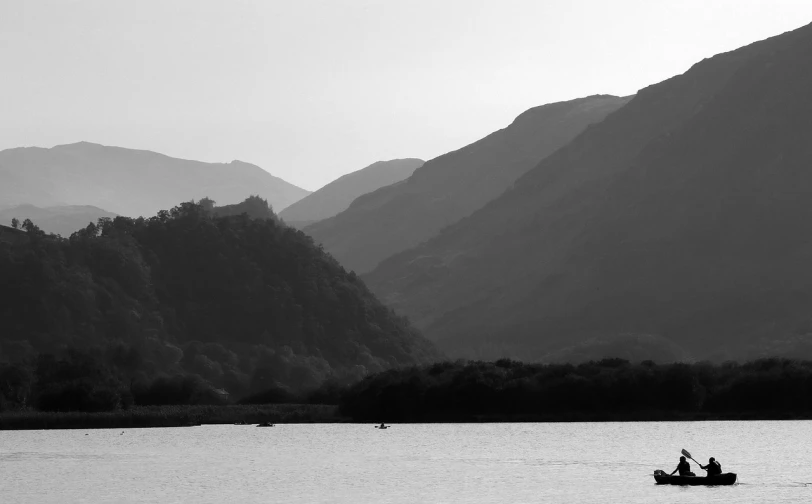 a couple of people riding on the back of a boat, a black and white photo, by Bedwyr Williams, plein air, a lake between mountains, 2 0 0 mm telephoto, 'lone dark figure'!!, heron