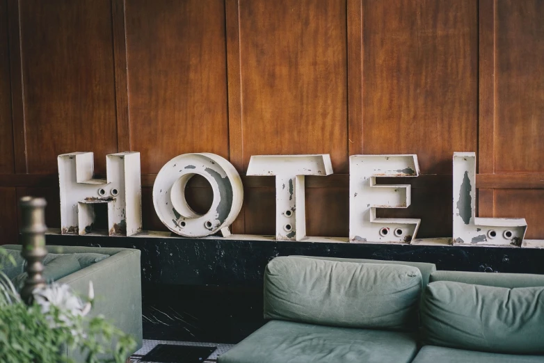 a hotel sign sitting on top of a wooden wall, unsplash, graffiti, white bed, large props, 1956, luggage