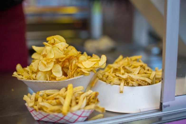 a couple of bowls of food sitting on top of a counter, inspired by Chippy, shutterstock, chips, 2 4 mm iso 8 0 0, food stall, flash photo