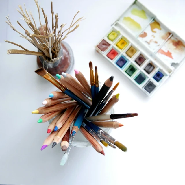 a glass filled with lots of different colored pencils, a watercolor painting, by Jaime Colson, pexels, process art, art toys on a pedestal, earthy colors, art station cfg _ scale 9, white wall coloured workshop
