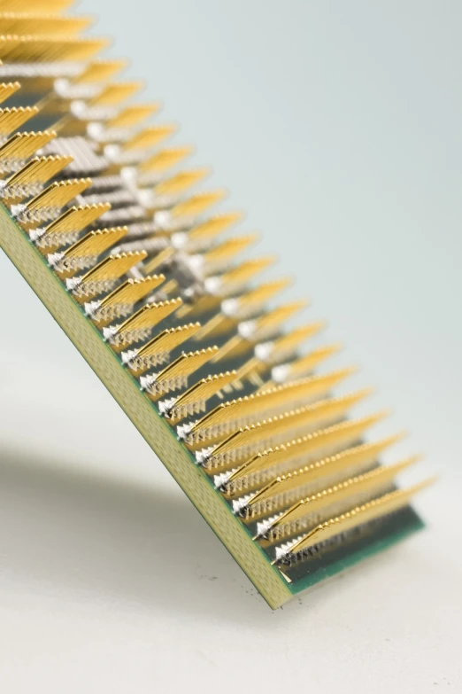 a close up of a yellow comb on a white surface, an ultrafine detailed painting, by Adam Chmielowski, reddit, computer art, circuit board processor block, stacked image, brass equipment and computers, highly detailed product photo