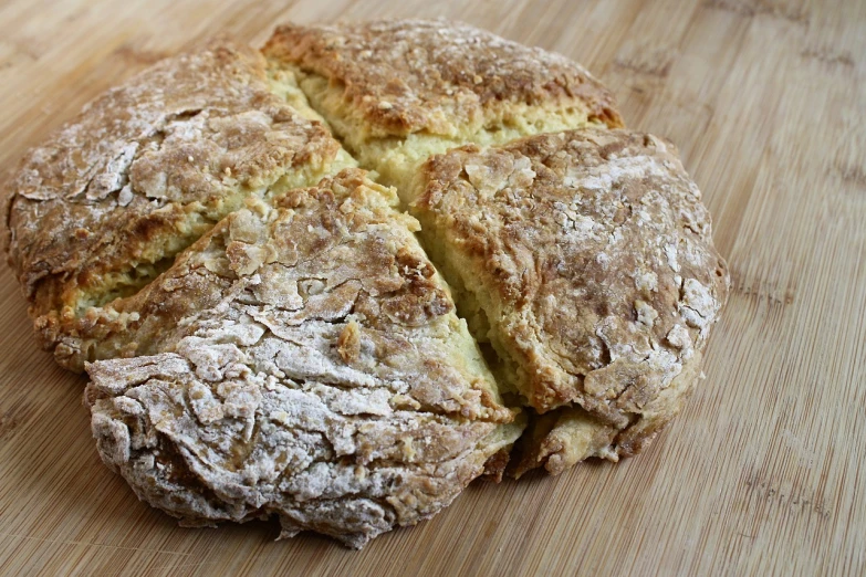 a loaf of bread sitting on top of a wooden cutting board, by David Garner, pixabay, celtic, round-cropped, crushed, covered in white flour