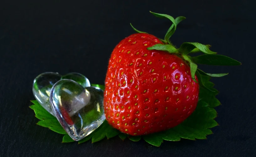 a strawberry sitting on top of a leaf next to a diamond, a still life, pixabay, romantic!!!, food photograph, image, snacks