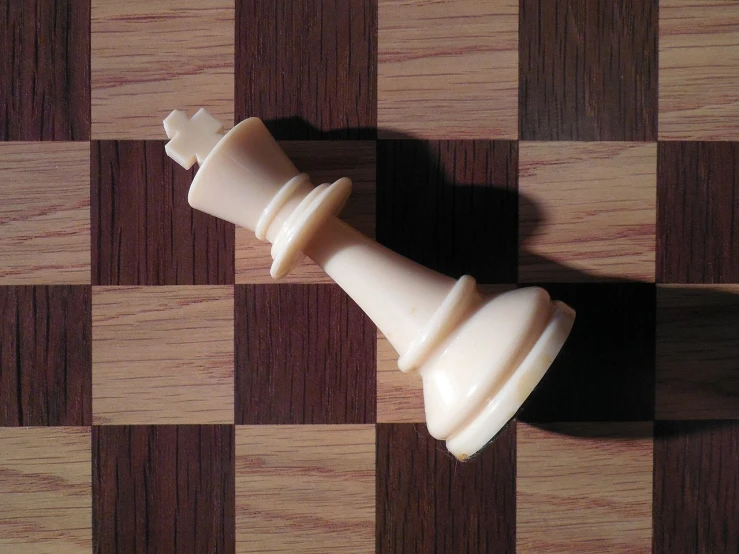 a white chess piece sitting on top of a chess board, a picture, flattened, a broad shouldered, seen from above, king