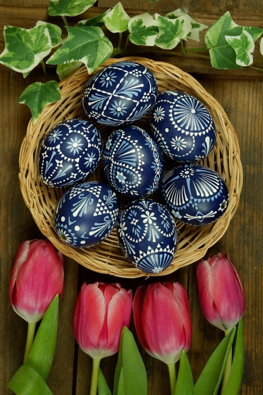 a basket filled with blue and white eggs next to pink tulips, by Maksimilijan Vanka, pixabay, folk art, navy-blue, detailed carved ornaments, [ organic, wood