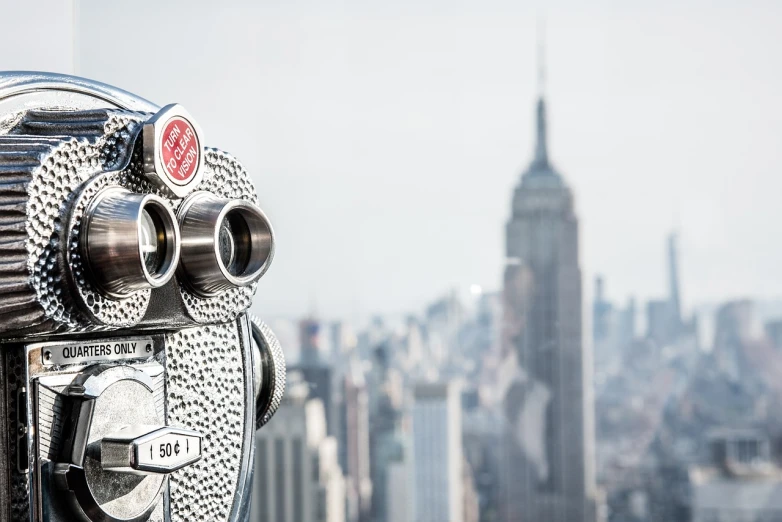 a close up of a telescope with a city in the background, modernism, empire state building, background image, i see you, bokeh. rule of thirds
