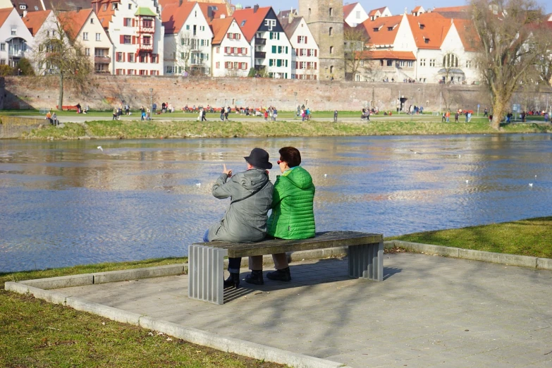 a couple of people that are sitting on a bench, a picture, by Hans Schwarz, datapipeline or river, older woman, photo taken from far, urban setting