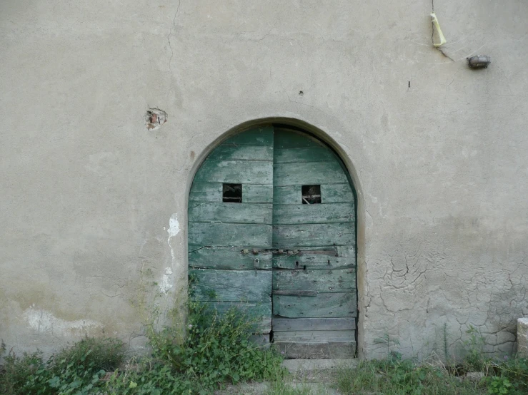 an old stone building with a green door, a picture, by Konrad Grob, discovered photo, pareidolia, basil gogos, taken in the late 2000s