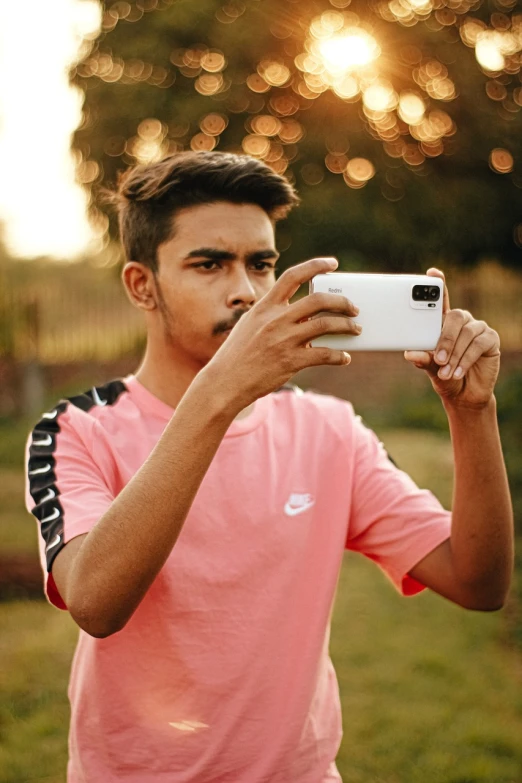 a man taking a picture with his cell phone, a picture, pexels, realism, pink white and green, male teenager, hindu aesthetic, wearing adidas clothing