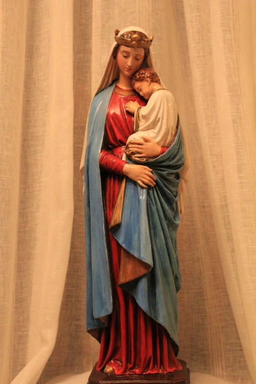 a statue of a woman holding a baby, by Juan O'Gorman, pixabay, in this church interior, blue and red color scheme, fully covered in drapes, 3/4 view realistic