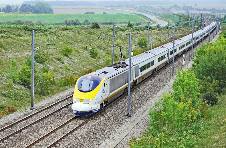 a large long train on a steel track, renaissance, eurostar, white and yellow scheme, conductor, border