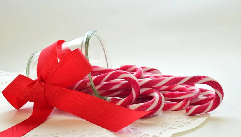 a glass jar filled with red and white candy canes, by Aleksander Gierymski, pixabay, pink, product introduction photo, ribbon, ham