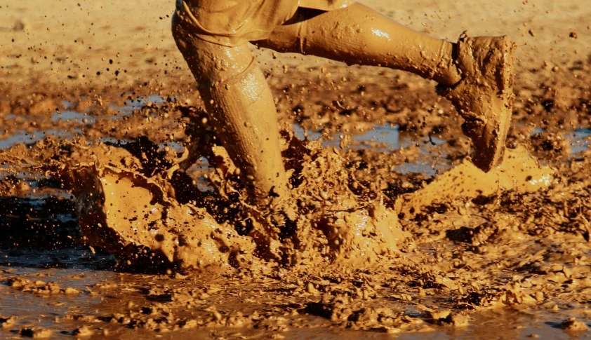 a man is playing in the mud with a frisbee, inspired by Samuel Silva, pixabay, ocher details, thumbnail, splash image, knee