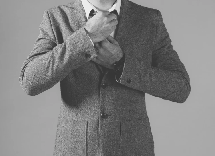 a man in a suit adjusting his tie, a black and white photo, inspired by Harrington Mann, tumblr, fine art, grey jacket, pose 4 of 1 6, matthew benedict, wearing wool suit