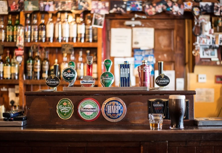 a bar filled with lots of different types of beer, by Matt Stewart, pexels, pub sign, beautiful surroundings, 1970s photo, a green