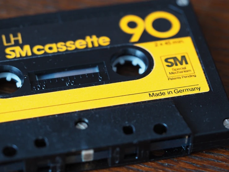 a cassette sitting on top of a wooden table, pixabay, yellow and black trim, '9 0 s, beautiful - n 9, case