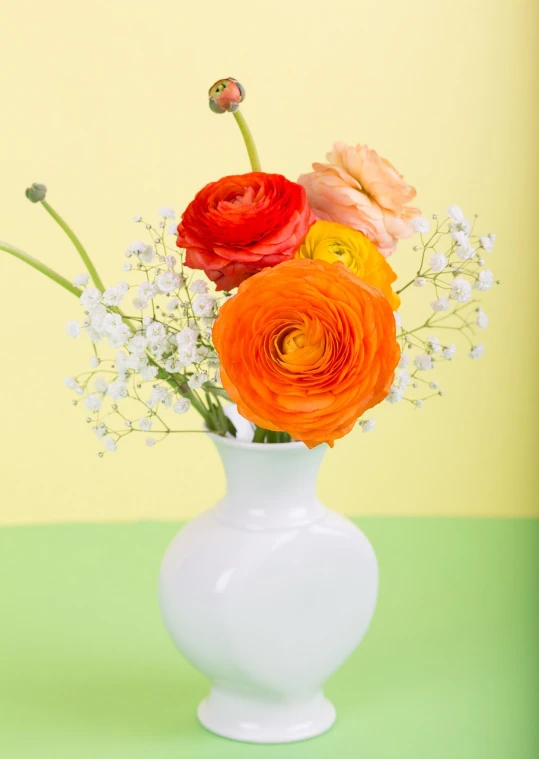 a white vase filled with orange and yellow flowers, a still life, pexels, pastel bright colors, close-up product photo, sleek white, buttercups