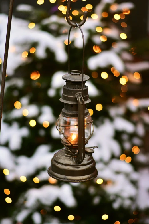 a lantern hanging in front of a christmas tree, a photo, by David Garner, pixabay, glowing snow, tiny details, carbide lamp, vanilla - colored lighting