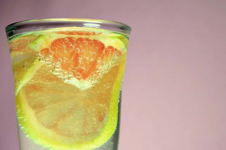 a glass of water with a slice of orange in it, dada, sliced grapefruit, jelly - like texture. photograph, bubbles ”, istockphoto