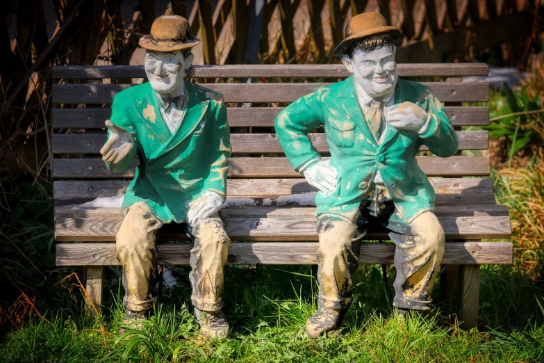 a couple of statues sitting on top of a wooden bench, by Edward Corbett, trending on pixabay, wearing green tophat, covered in mud, bossons vintage chalkware, ireland
