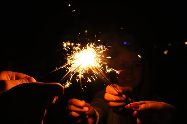 two people holding sparklers in their hands, a picture, by Caroline Mytinger, wikimedia commons, fire flies, girls, 2 0 1 0 photo