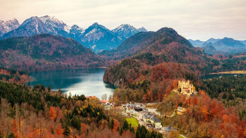 a lake surrounded by trees with mountains in the background, a tilt shift photo, by Juergen von Huendeberg, pixabay, renaissance, red castle in background, autum, a high angle shot, featured