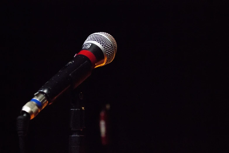 a close up of a microphone on a stand, a picture, happening, standing with a black background, on a stage, far - view, completely empty