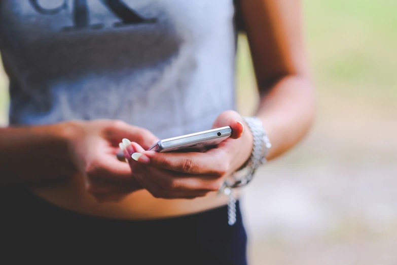 a close up of a person holding a cell phone, a photo, girl, outdoor photo