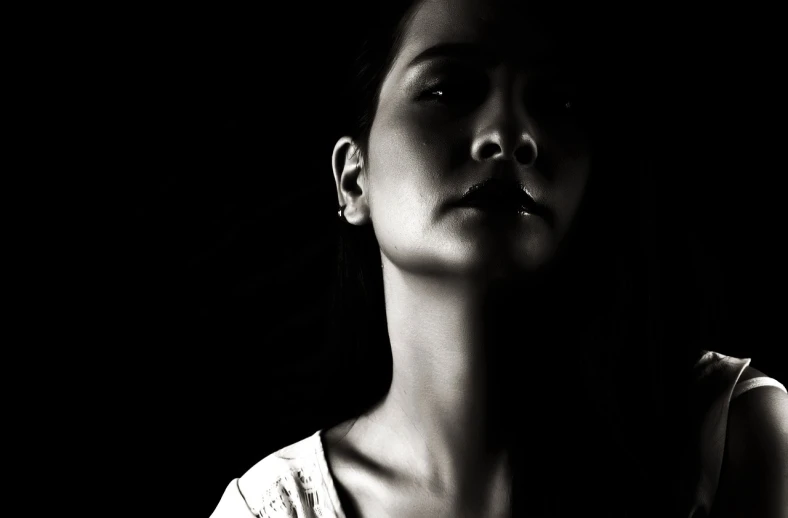 a black and white photo of a woman's face, pexels, figure in the darkness, young woman looking up, a young asian woman, intimidating woman