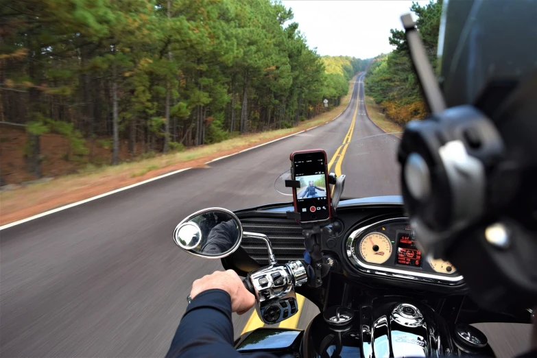 a man riding on the back of a motorcycle down a road, a picture, pixabay, holding a very advance phone, cockpit view, tx, inside a grand