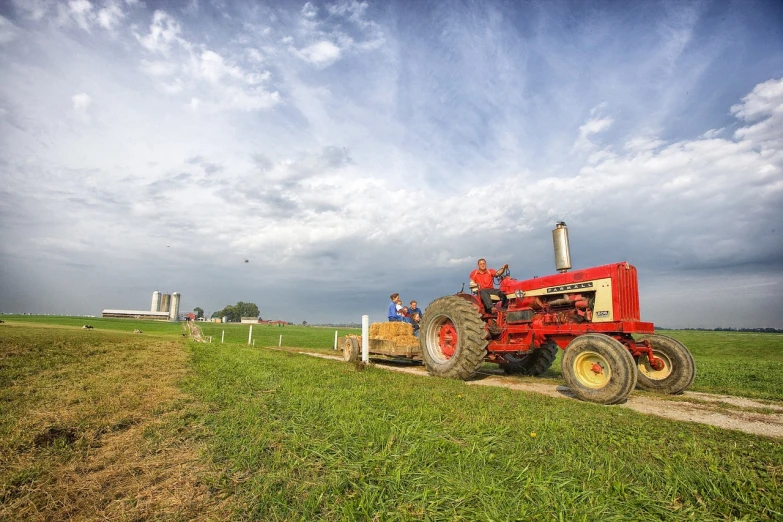 a red tractor sitting on top of a lush green field, a portrait, by Jim Nelson, flickr, wide angle dynamic action shot, old american midwest, villagers busy farming, bright sky