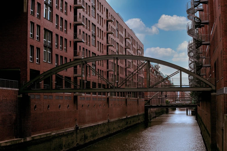 a bridge over a river next to tall buildings, a photo, by Werner Gutzeit, warehouses, brick, steel archways, wikimedia commons