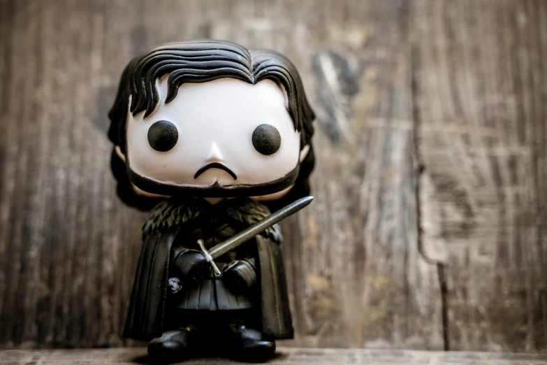 a close up of a figurine of a man with a sword, a cartoon, pexels, funko pop”, john snow, on wood, with his long black hair