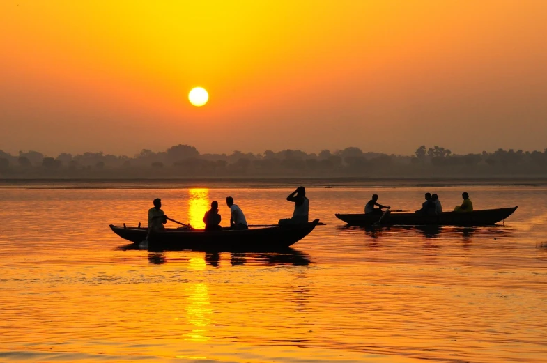 people in boats floating at sunset on the water