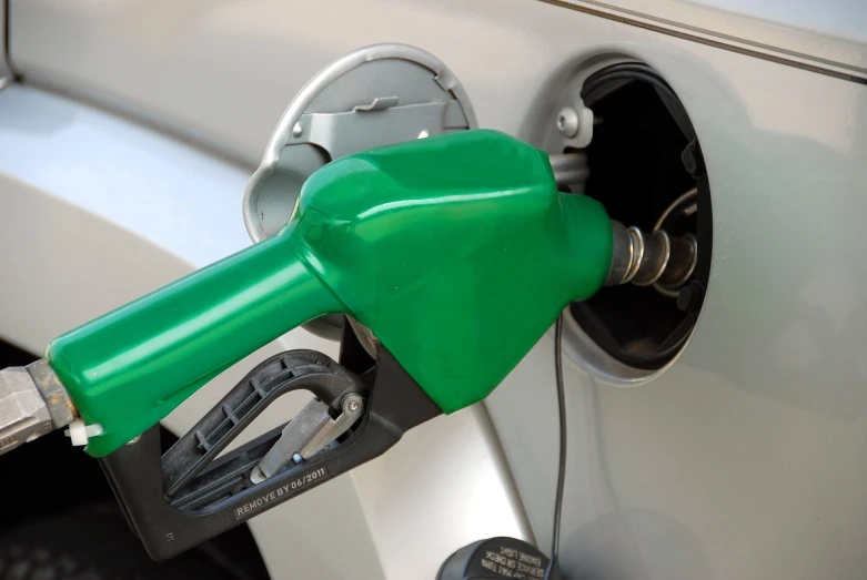 a green gas pump is attached to a grey car