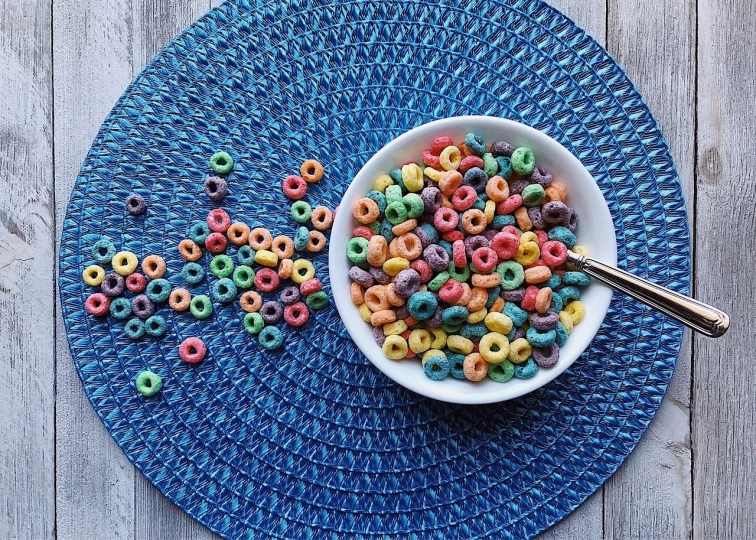 bowl with cereals and spoon sitting on blue placemat