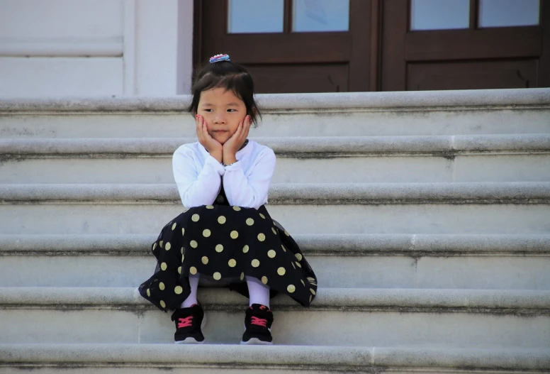 a  sitting on steps holding her hand to her face