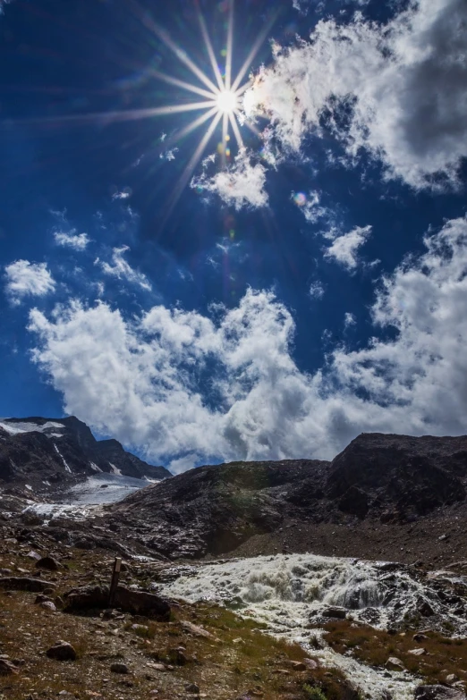 the sun shines brightly on a mountain in front of mountains