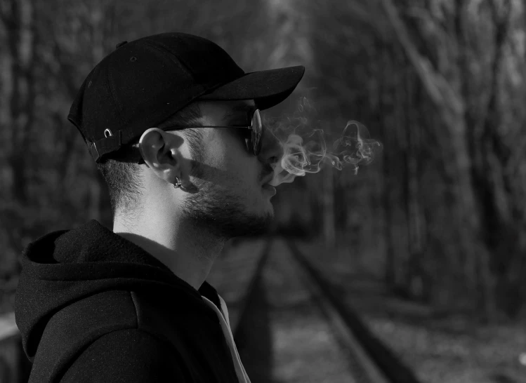 a man standing next to railroad tracks with an empty pipe sticking out of his head