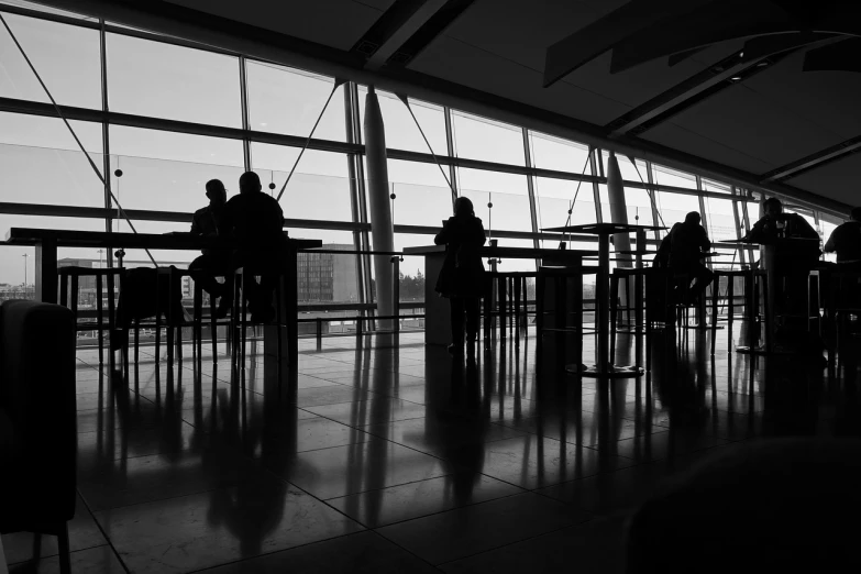 people are sitting at tables inside of an airport terminal