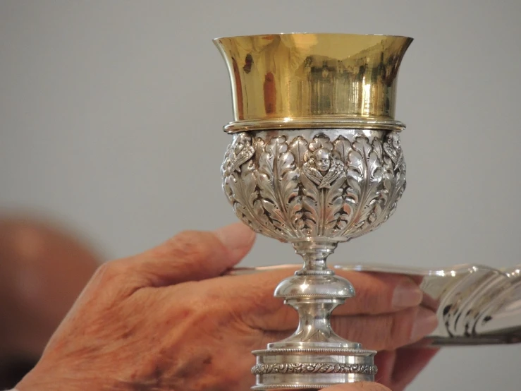 the hand is holding an ornate cup on it
