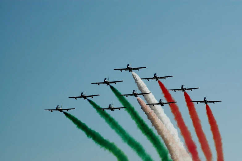 several airplanes with red white and green smoke