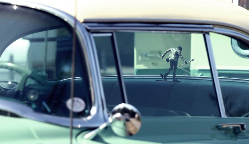 reflection of a man with a baseball bat in the side view mirror of a car