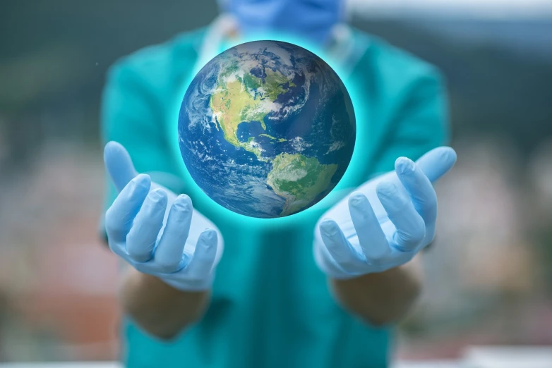 someone in a surgical suit holds a blue earth in their hands