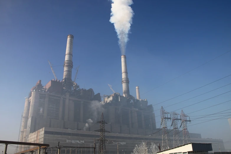 smokestacks loom as a train passes below a factory