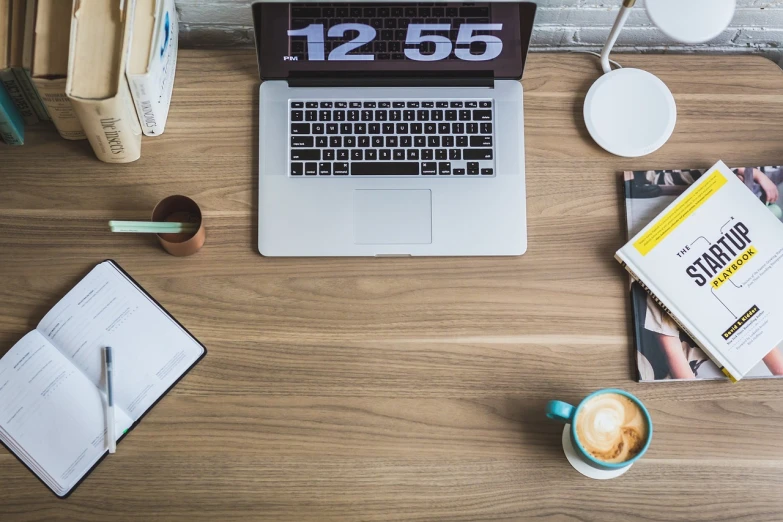 a white laptop sits on top of a desk next to papers